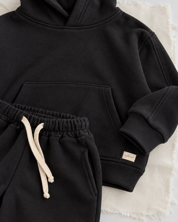 RG Brand RG1786 siyah çocuk kapüşonlu eşofman takımı, 3–9 yaş; kumaş, cep ve kordon yakın planı.