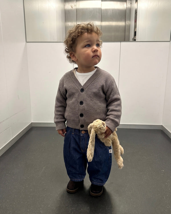 Bej Selanik triko hırka ve mavi pantolon giyen bebek, tavşan oyuncağıyla tam boy | RG397