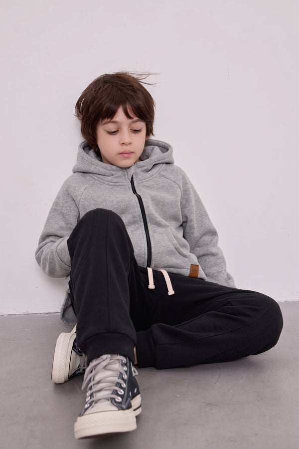 Gri kapüşonlu RG1791 sweatshirt ve siyah jogger giyen oturan erkek çocuk