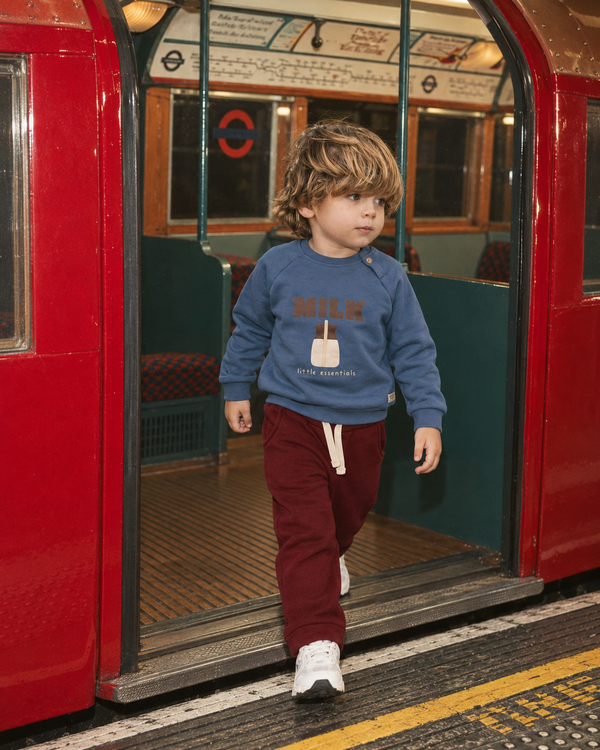 İndigo RG405 Milk figürlü çocuk sweatshirt, kırmızı metro kapısında yürüyen model