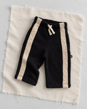 RG Brand RG406 siyah bebek pantolonu; ekru kumaş zeminde çapraz yerleşim, açık renk şeritler ve yan etiket.