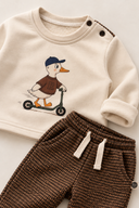 RG415 baby outfit detail showing the duck print, shoulder buttons and waistband and fabric of the beige checked trousers.