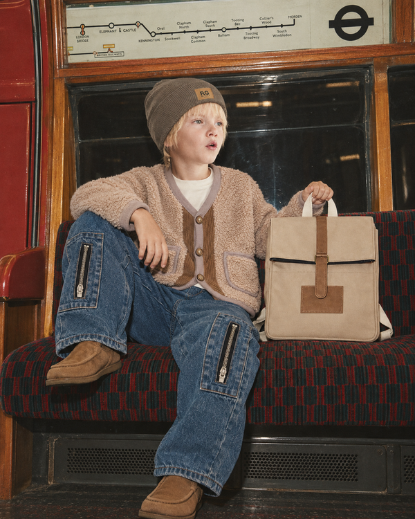 RG1780 taş peluş hırka ve RG1775 denim pantolon giyen çocuk, RGBAG3 çanta ile otururken